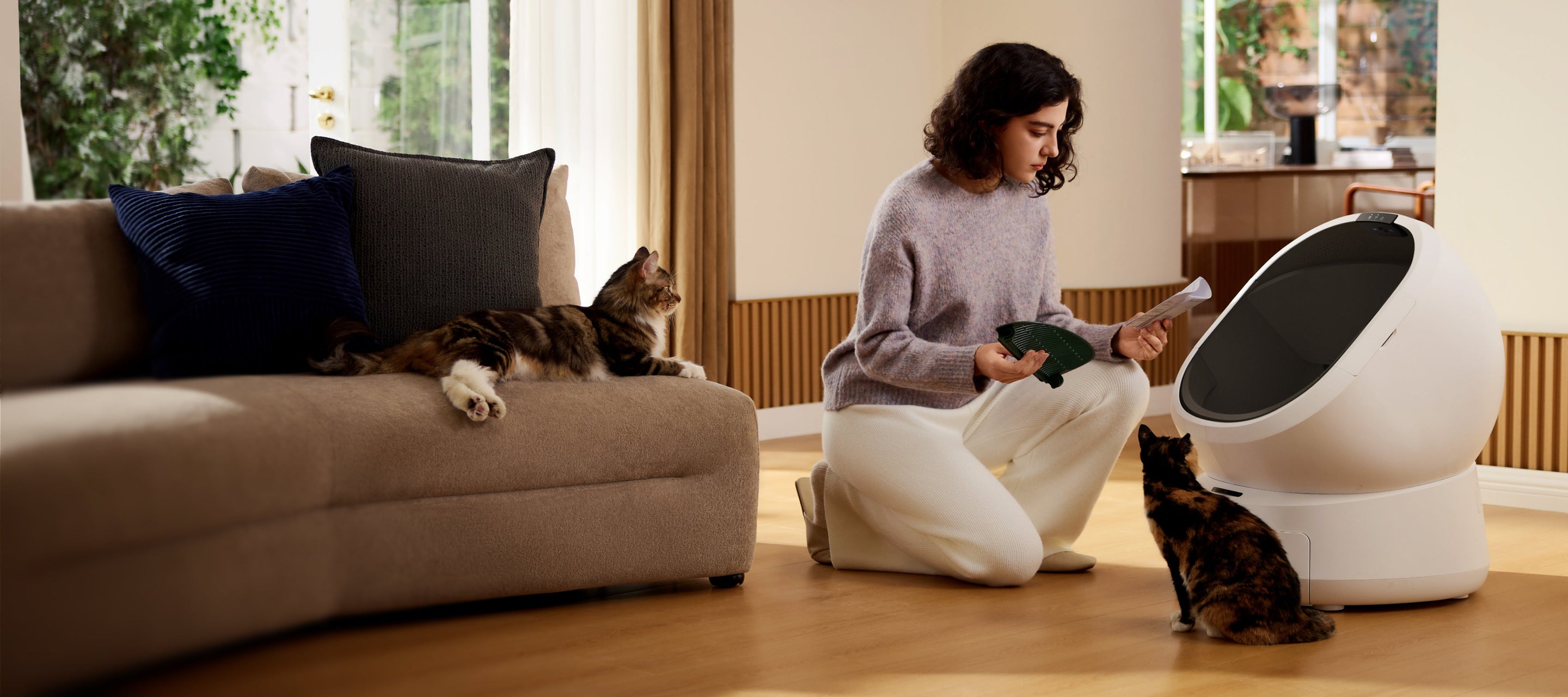 Petlibro PETLIBRO Katzentoilette, Frau kniet daneben; Katze am Sofa, Haustier davor; Brunnen und automatischer Futterspender im Raum.