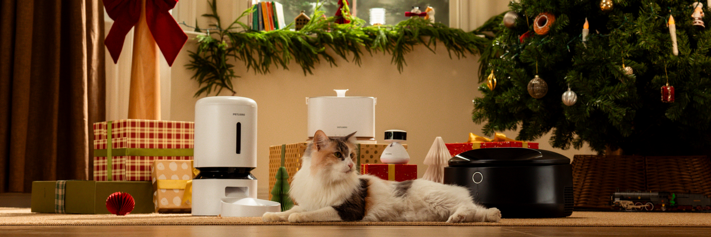 Petlibro PETLIBRO Brunnen, Katzentoilette und automatischer Futterspender neben ruhender Katze im festlichen Wohnzimmer mit Geschenken